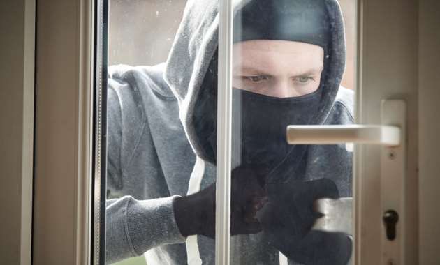 A burglar breaking into a home via a door with sensors.
