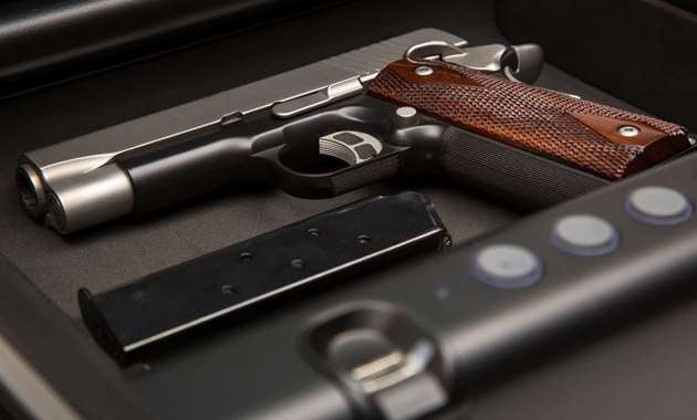 A handgun being stored in a safe with other valuables.