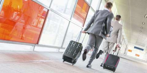 Rear view of middle aged businessmen with luggage rushing on railroad platform