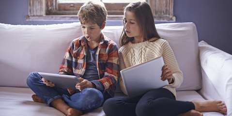 young brother and sister using their digital tablets