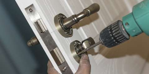 Man installing door lock with drill