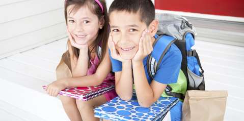 Two smiling kids on a porch