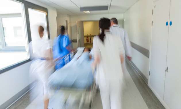 Healthcare personnel rushing a patient through a hospital.